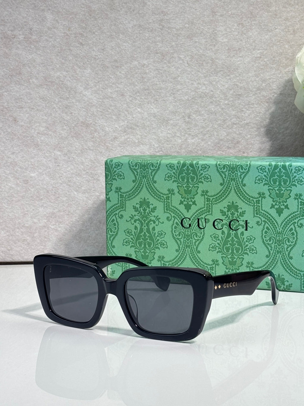 Gucci sunglasses with dark square frames, gray lenses, and side logo accents