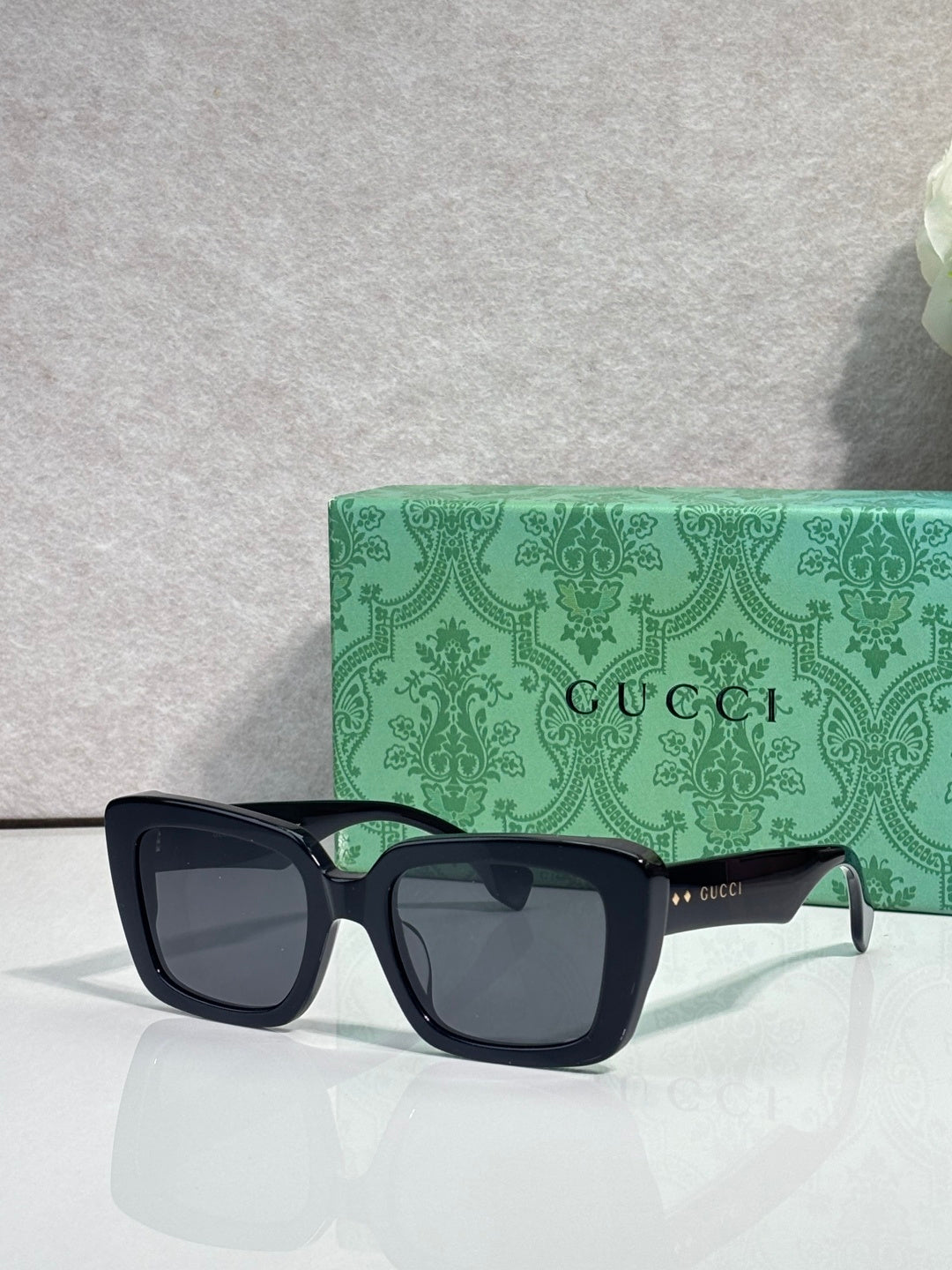 Gucci sunglasses with dark square frames, gray lenses, and side logo accents