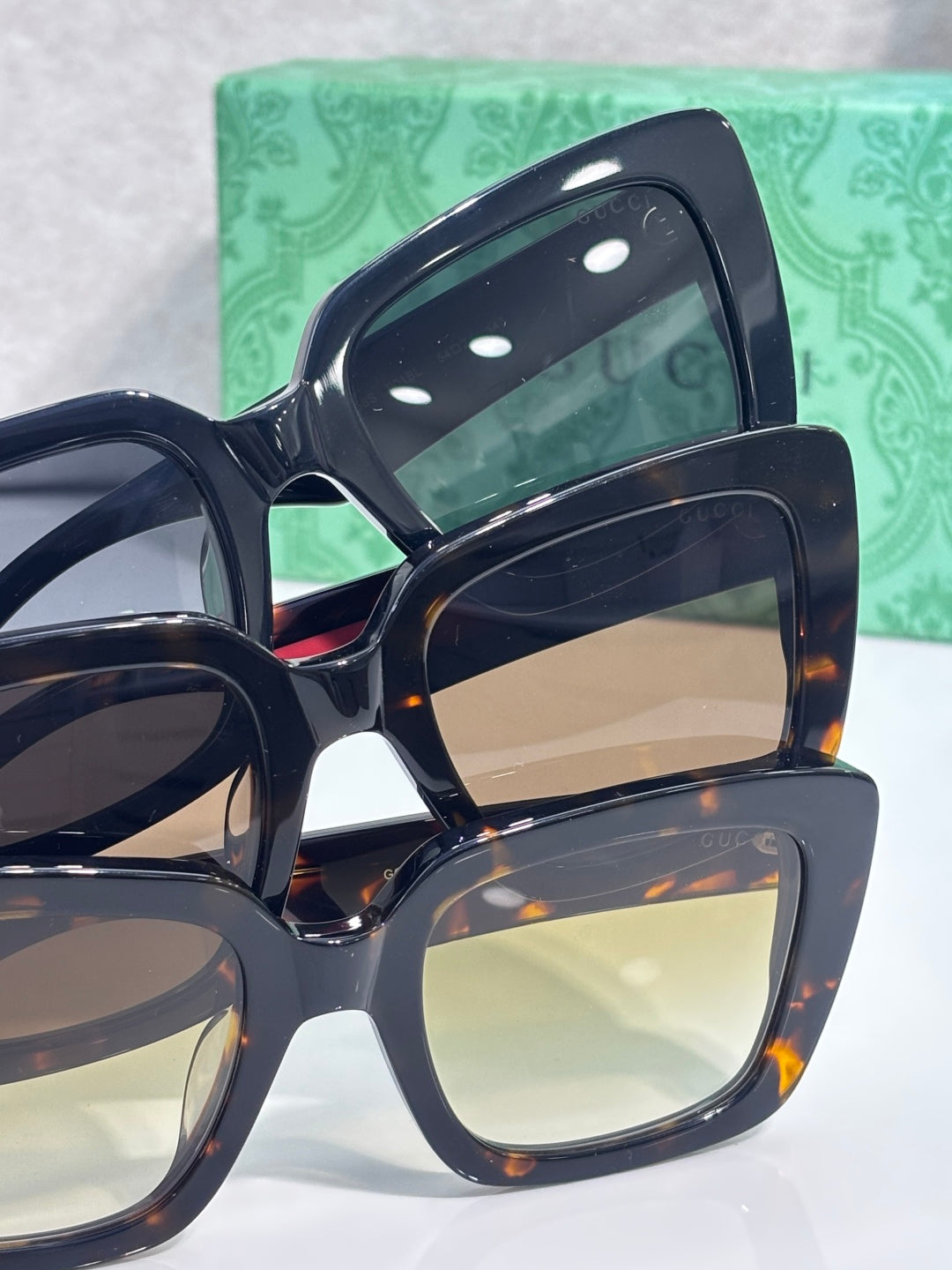 Gucci sunglasses stack close-up with dark frames and multi-tinted lenses