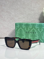 Gucci sunglasses with dark frames, brown-tinted lenses, and a green logo case behind