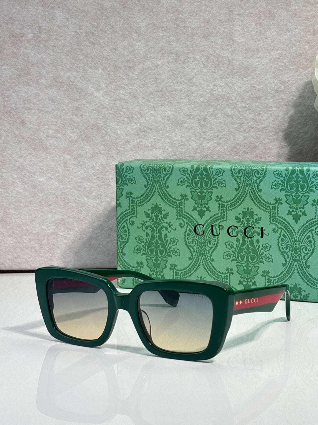 Gucci sunglasses with green-tinted dark frames and light lenses