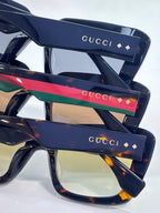 Gucci sunglasses close-up: dark temples with red-and-green stripes and gold GUCCI logos