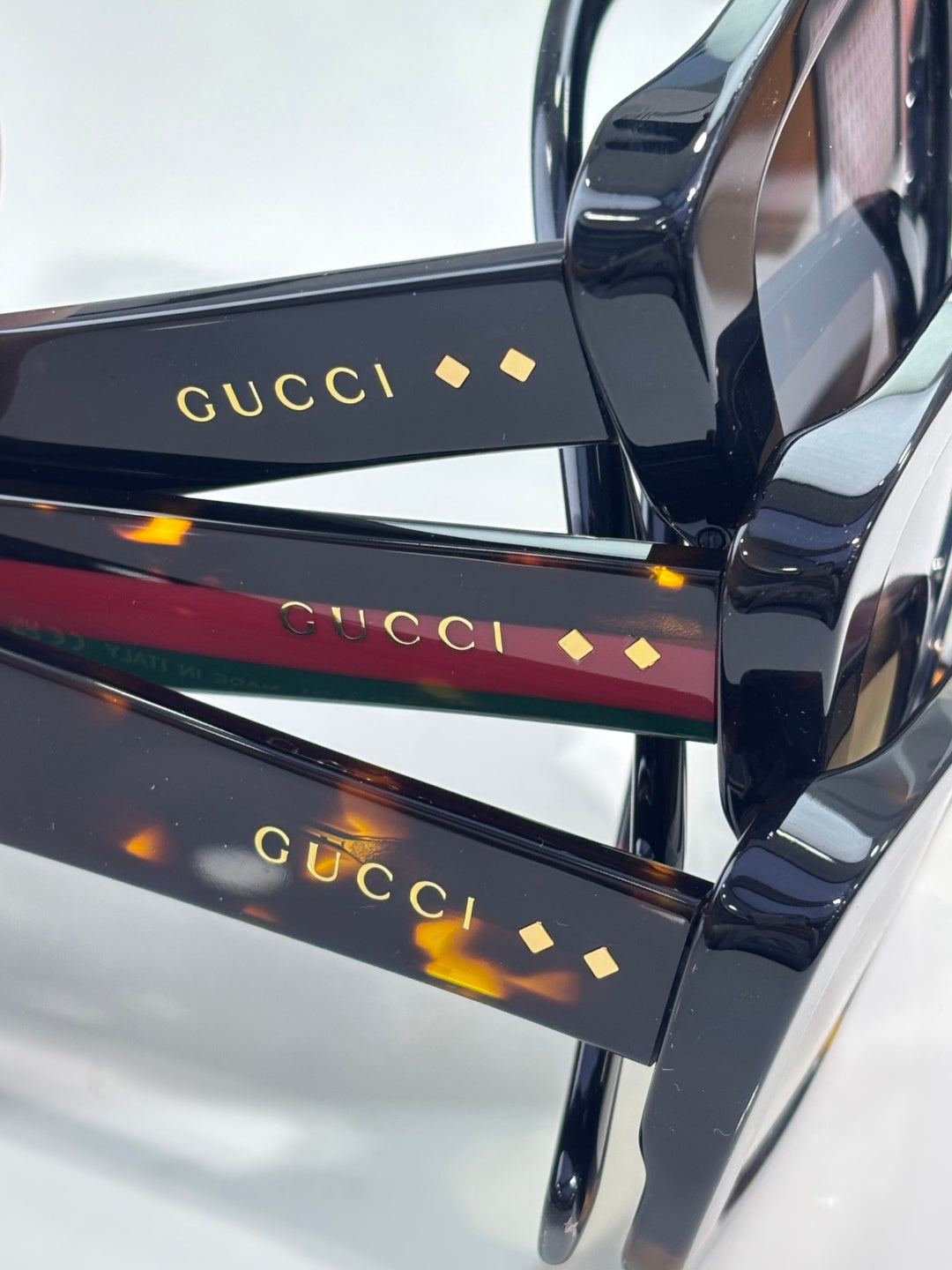 Gucci sunglasses close-up: black temples with gold GUCCI lettering and small diamond marks