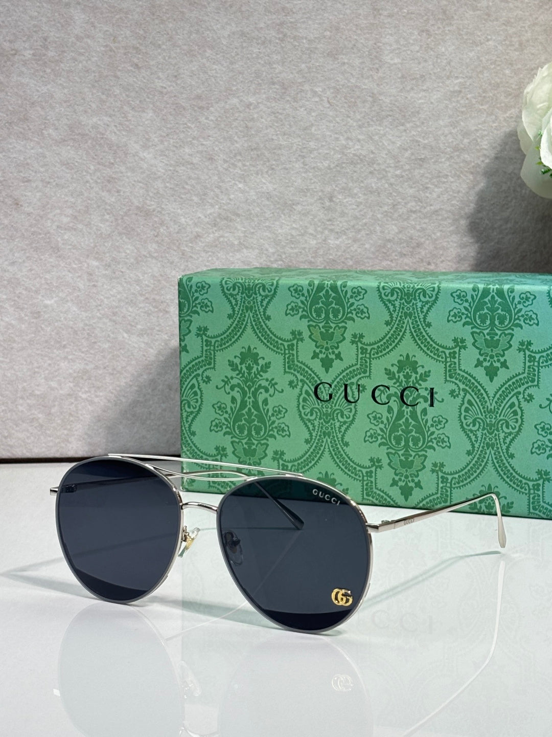 Sunglasses with dark round lenses, light gold frame, slim temples with logo