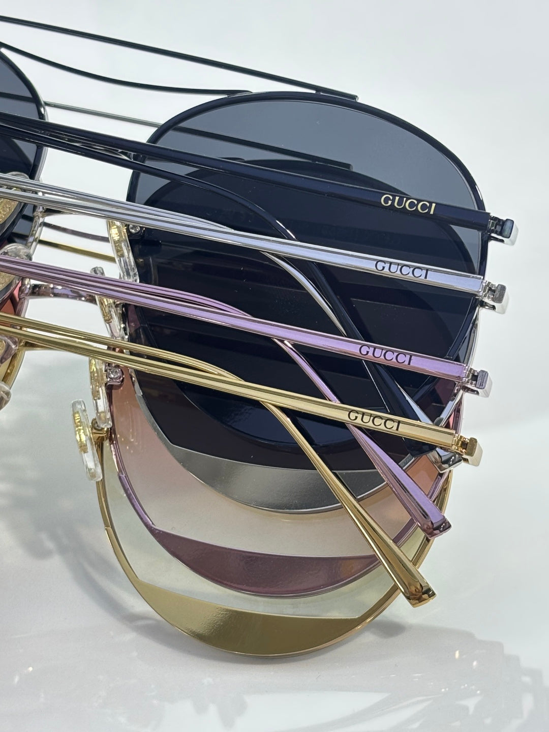 Stack of sunglasses with dark lenses and gold-tone frames, slim metal temples