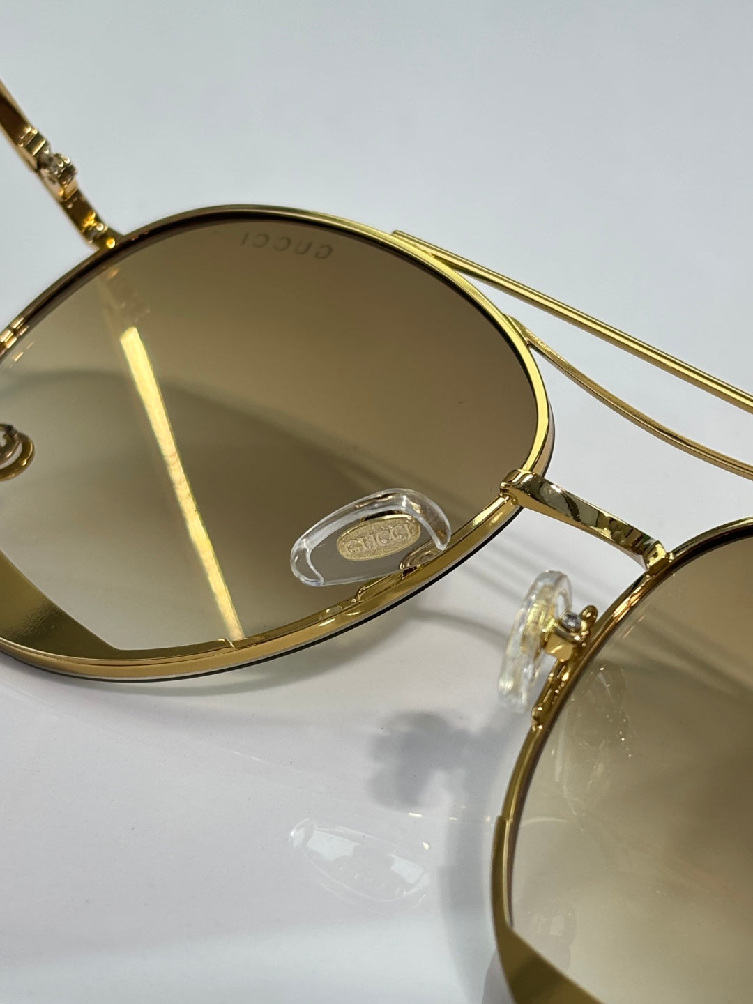 Close-up of gold-tone sunglass frame with engraved logo on temple