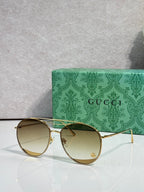 Sunglasses with warm gold-tinted round lenses, gold-tone frame, slim temples