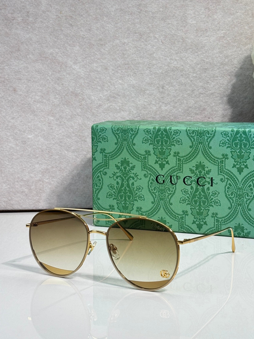 Sunglasses with warm gold-tinted round lenses, gold-tone frame, slim temples