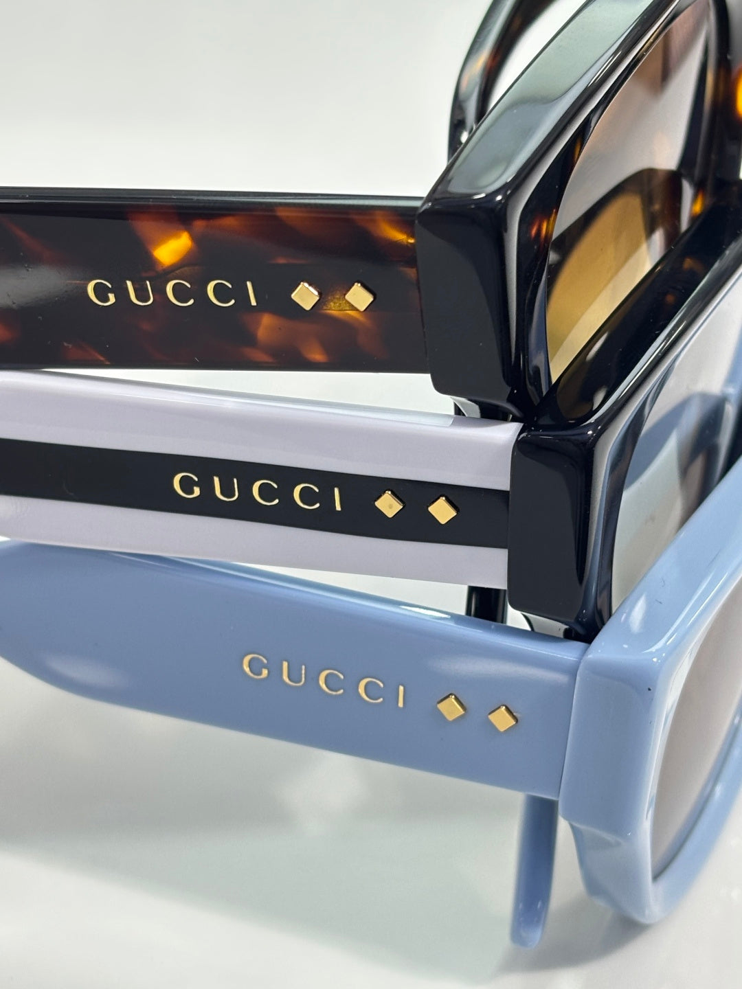 Gucci eyeglass case detail with stacked boxes and gold logo text, glossy finish