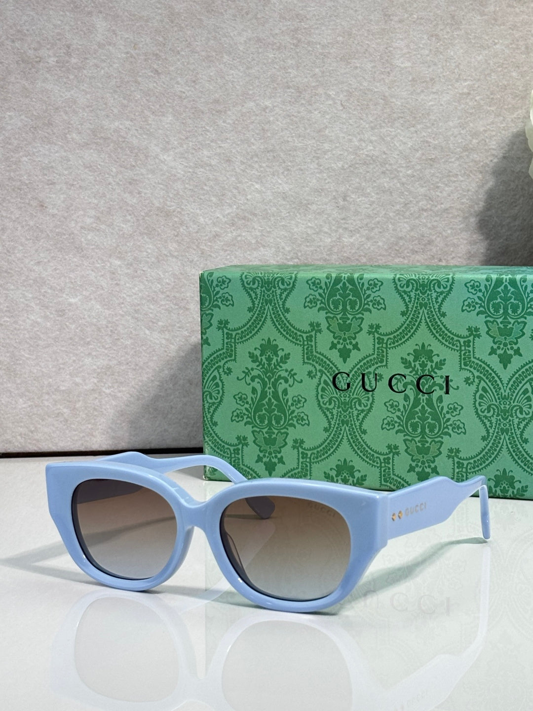 Gucci sunglasses with light blue frame and tinted lenses, rounded rectangular cat-eye style