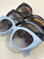 Gucci sunglasses with light blue and black frames, rounded square lenses, glossy finish