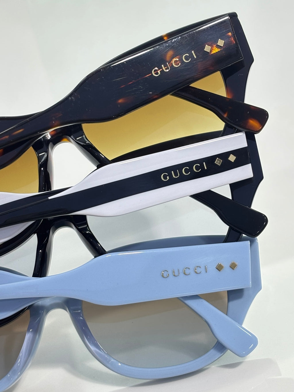 Gucci sunglasses stack showing black and light blue frames with gold logo details