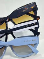 Gucci sunglasses stack showing black and light blue frames with gold logo details