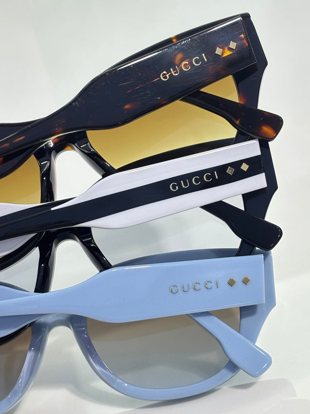 Gucci sunglasses stack showing black and light blue frames with gold logo details