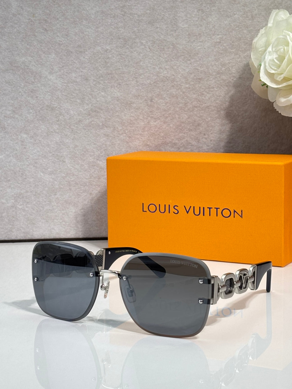 Sunglasses with dark tinted lenses and metal frame; chunky gold chain-link temple detail.