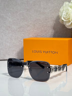 Sunglasses with dark tinted lenses and black frame; gold chain-link temple with logo.