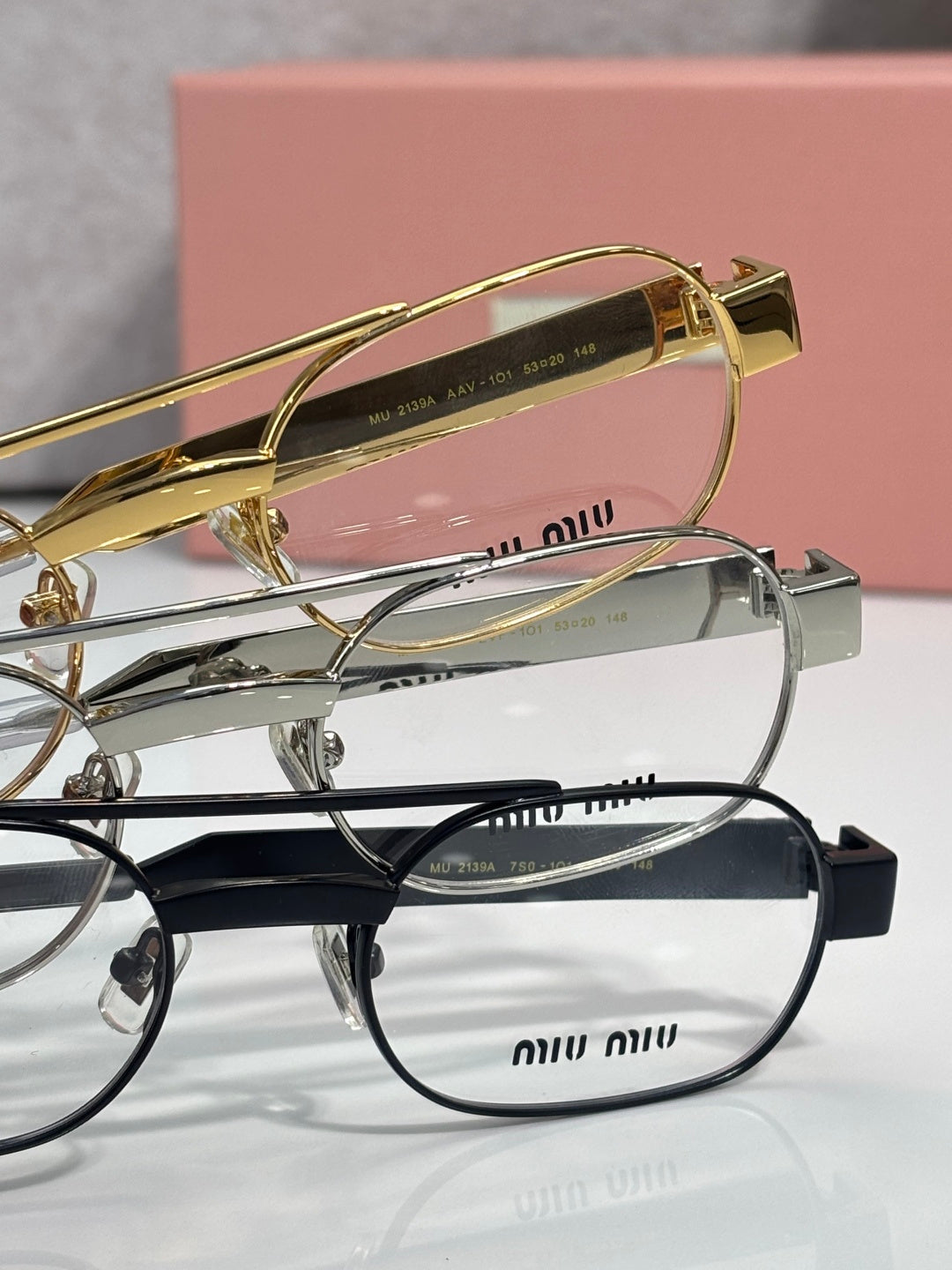 Stacked eyeglasses: gold, silver, and dark frames with clear lenses and curved temple arms