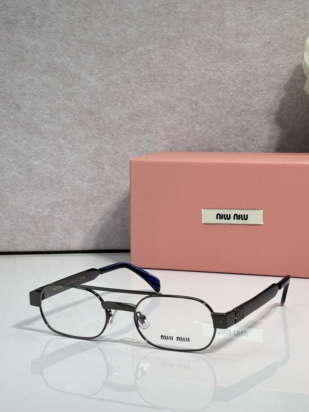 Dark blue eyeglasses with clear lenses and black temple arms, slim metal frame with logo plate