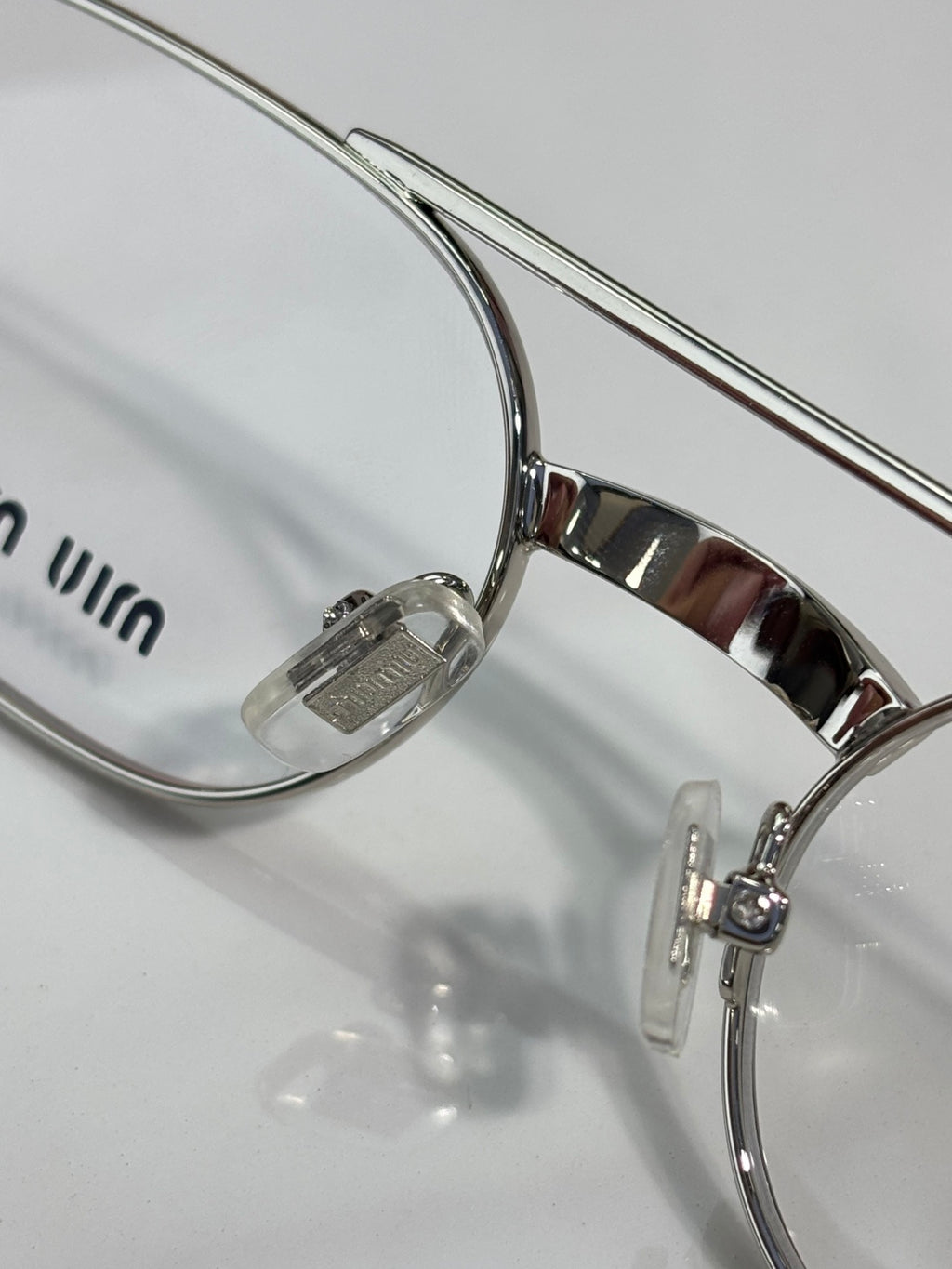 Close-up of silver eyeglasses frame with clear lens and curved temple arm