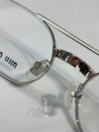 Close-up of silver eyeglasses frame with clear lens and curved temple arm