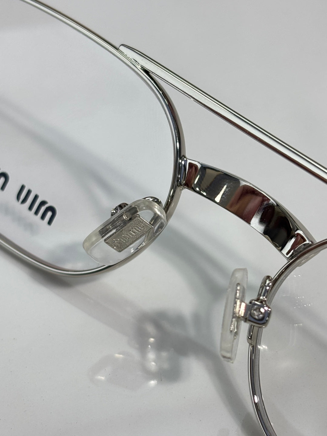 Close-up of silver eyeglasses frame with clear lens and curved temple arm