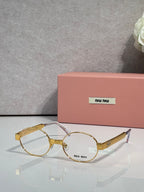 Round metal eyeglass frames with clear lenses, mixed gold and silver tones, Miu Miu logo.