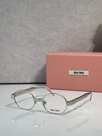 Round metal eyeglass frames with clear lenses, silver-toned arms, Miu Miu logo.