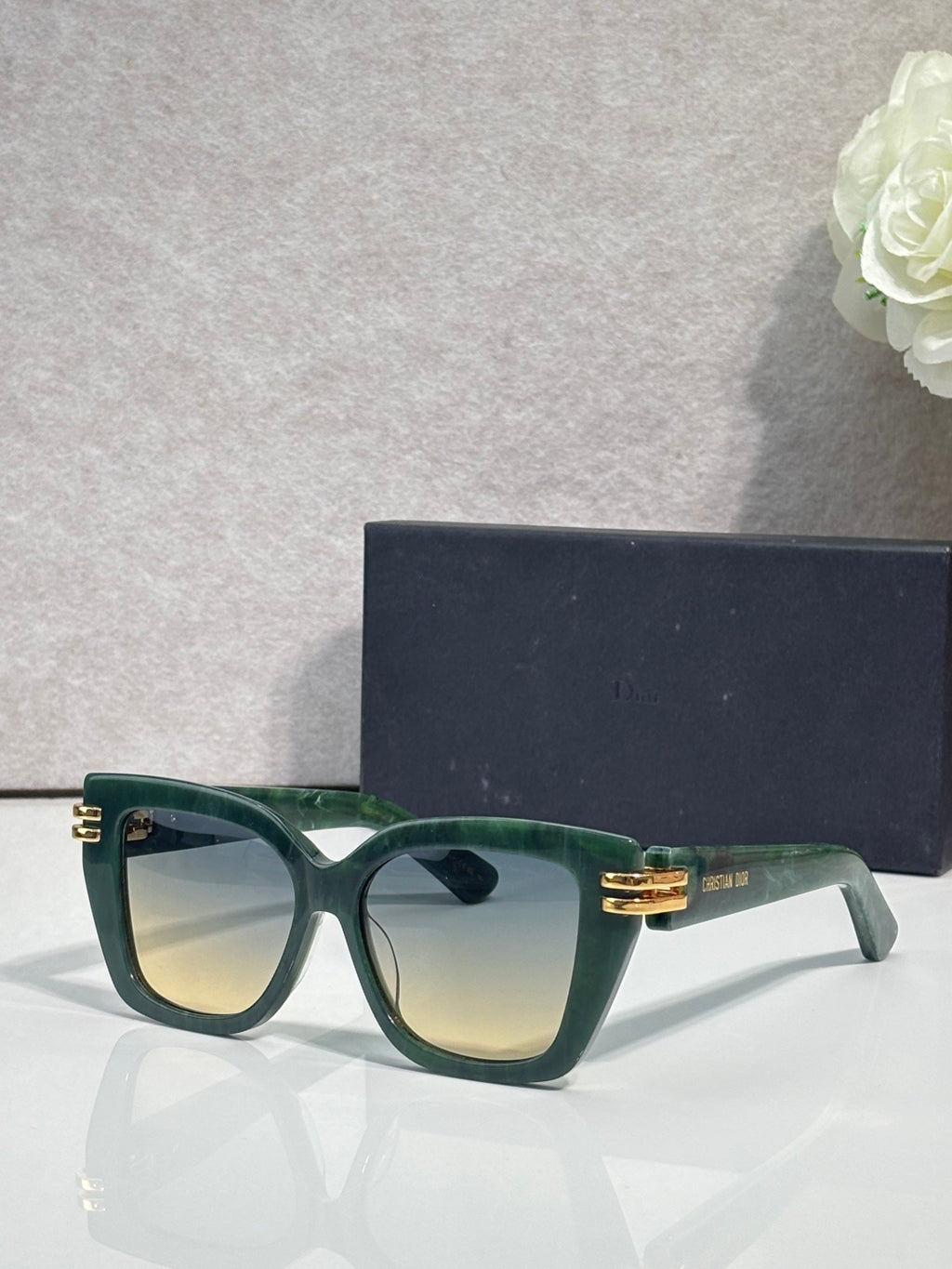Dior eyeglasses with dark green frames and gold bar details, tinted gradient lenses