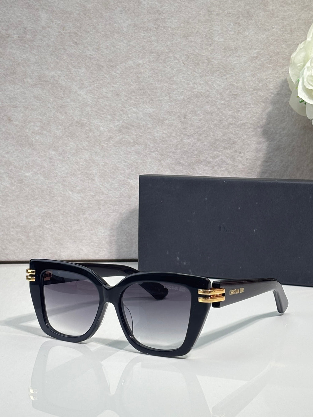 Dior eyeglasses with black frames and gold bar details, clear-tinted lenses