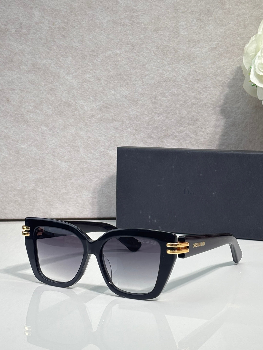 Dior eyeglasses with black frames and gold bar details, clear-tinted lenses