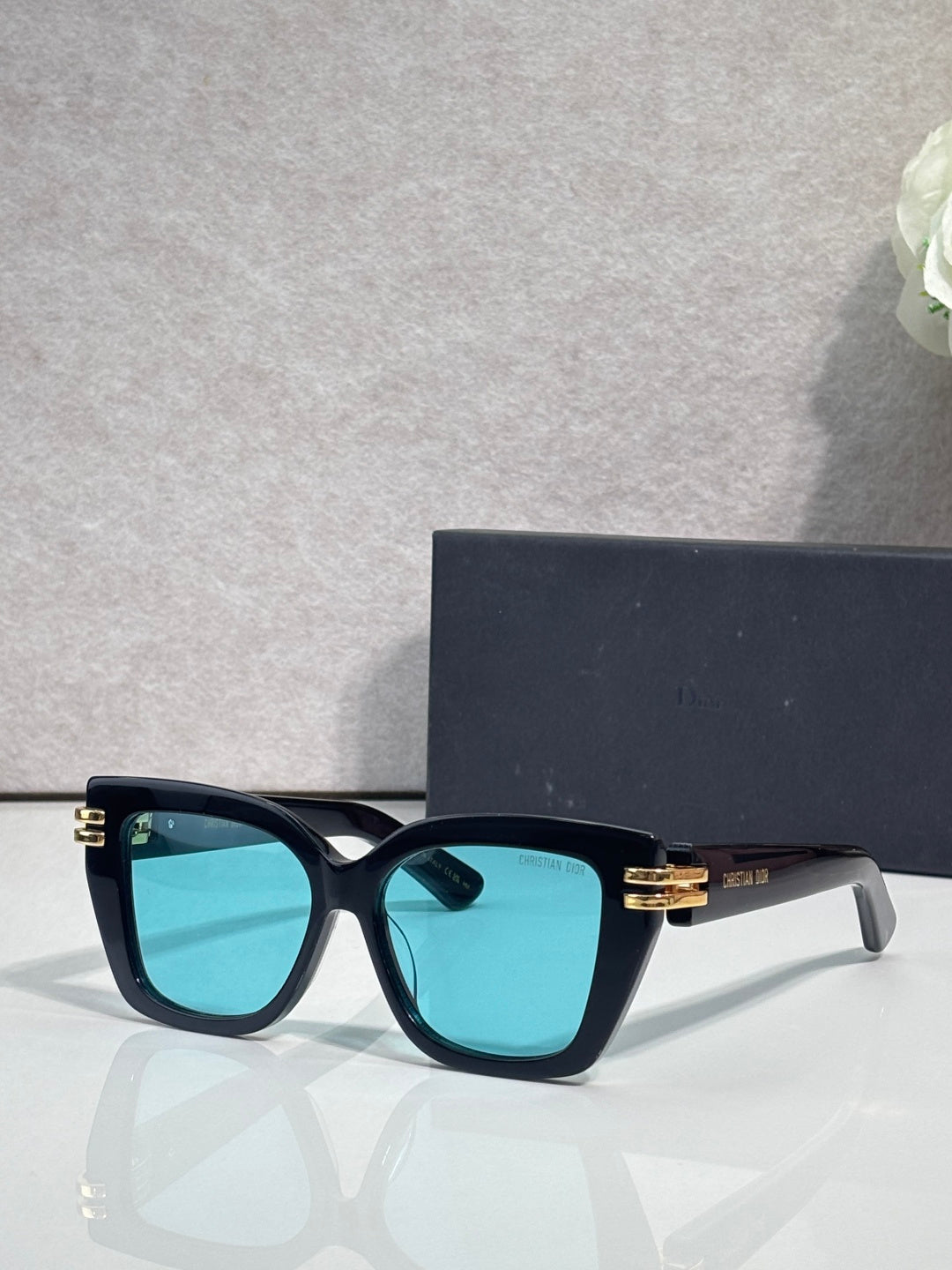 Dior eyeglasses with dark teal frames and gold bar details, turquoise tinted lenses