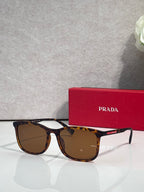 Prada sunglasses with dark brown lenses and tortoiseshell frames, beside red logo case