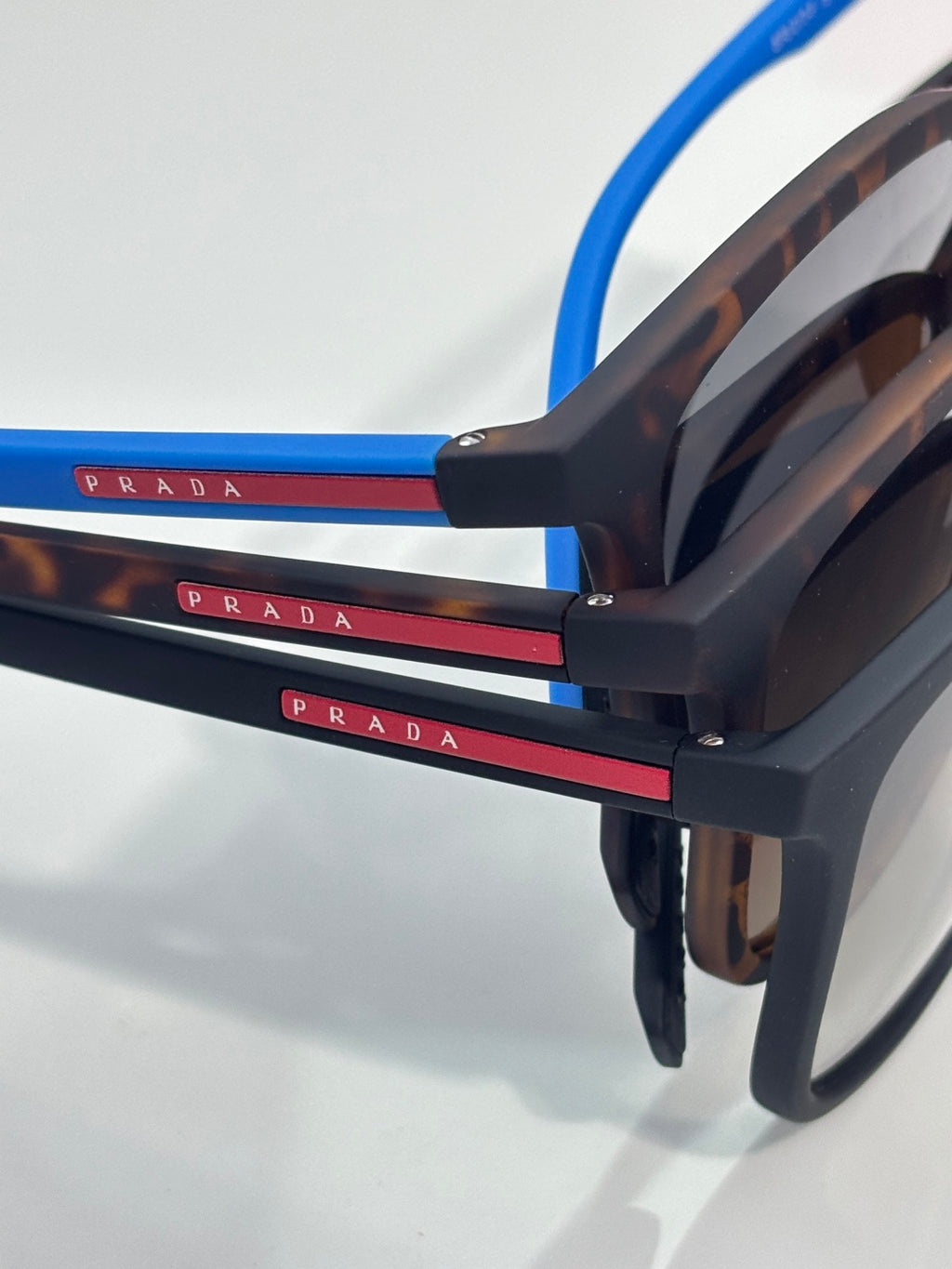 Prada sunglasses side view with dark tortoiseshell temples, blue accents, and logo bar