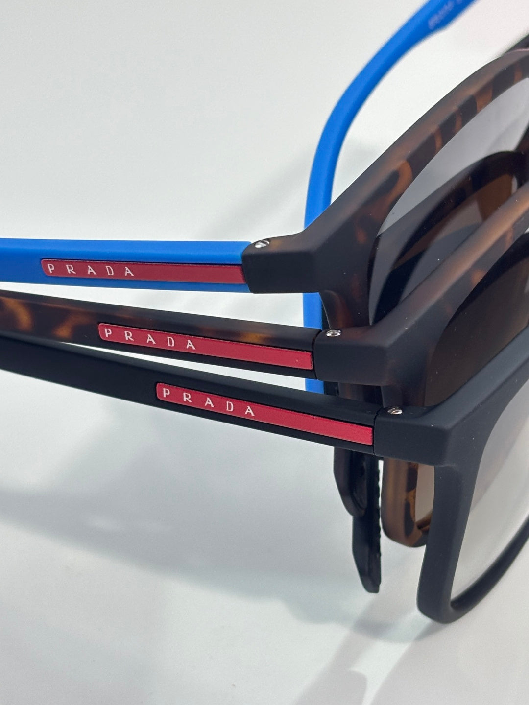 Prada sunglasses side view with dark tortoiseshell temples, blue accents, and logo bar