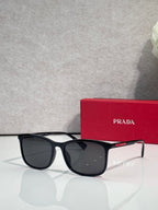 Prada sunglasses with dark lenses and black tortoiseshell frames, next to red logo case
