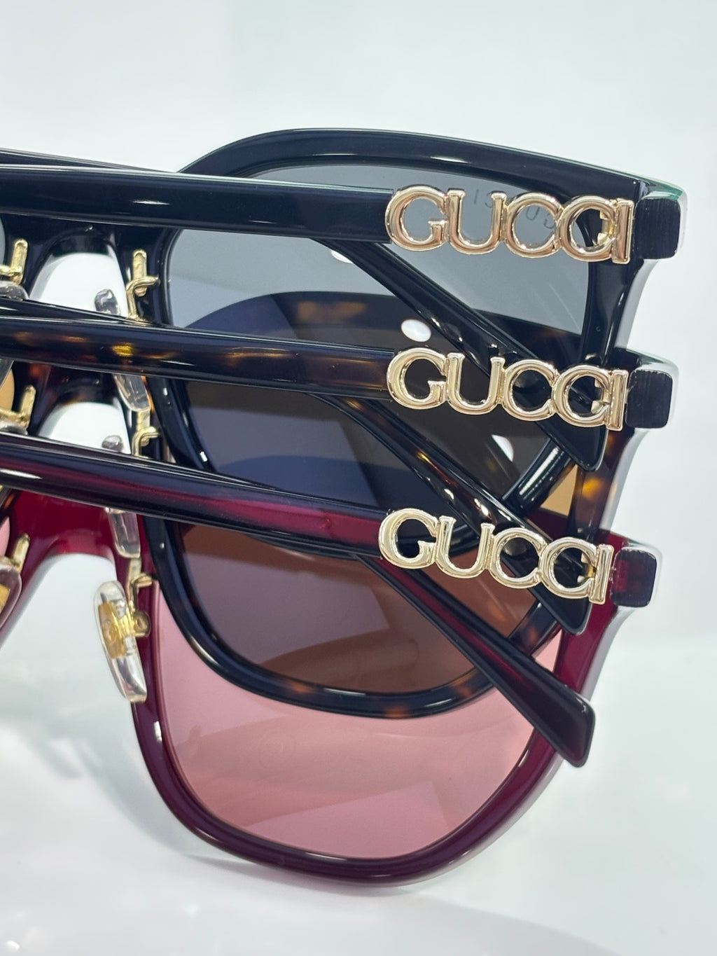 Stacked navy sunglasses with gold Gucci lettering on temples and tinted lenses