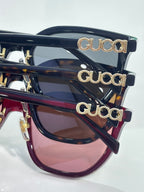 Stacked navy sunglasses with gold Gucci lettering on temples and tinted lenses