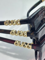 Black sunglasses with gold-toned decorative temple hardware and tinted lenses