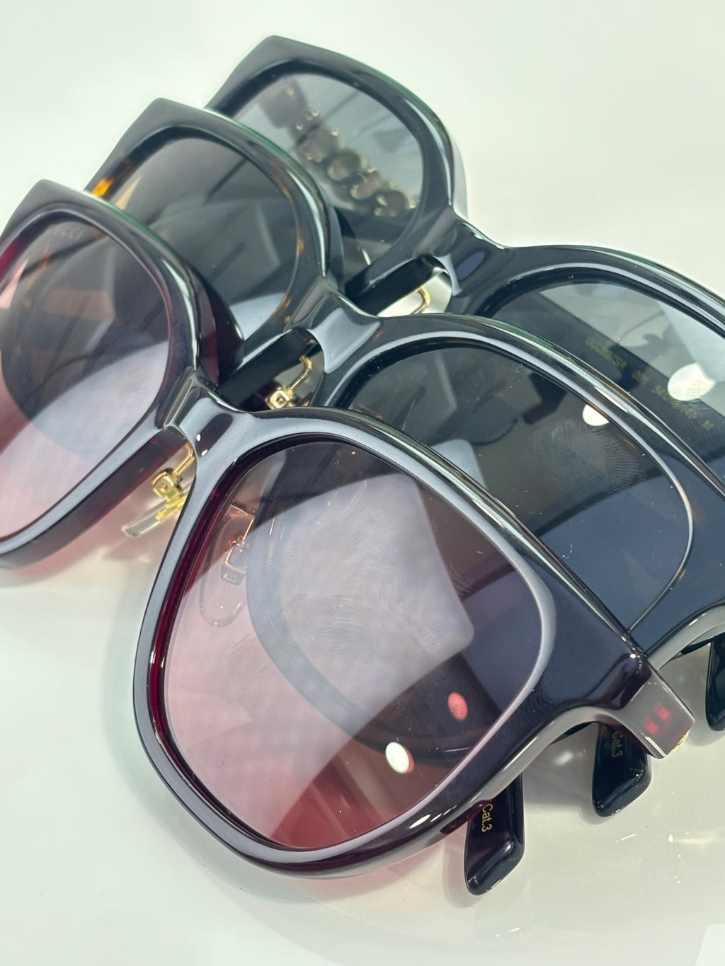 Assorted navy and burgundy sunglasses with gold accents and tinted lenses