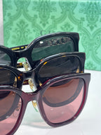 Dark navy square sunglasses with gold Gucci text on temple and tinted lenses