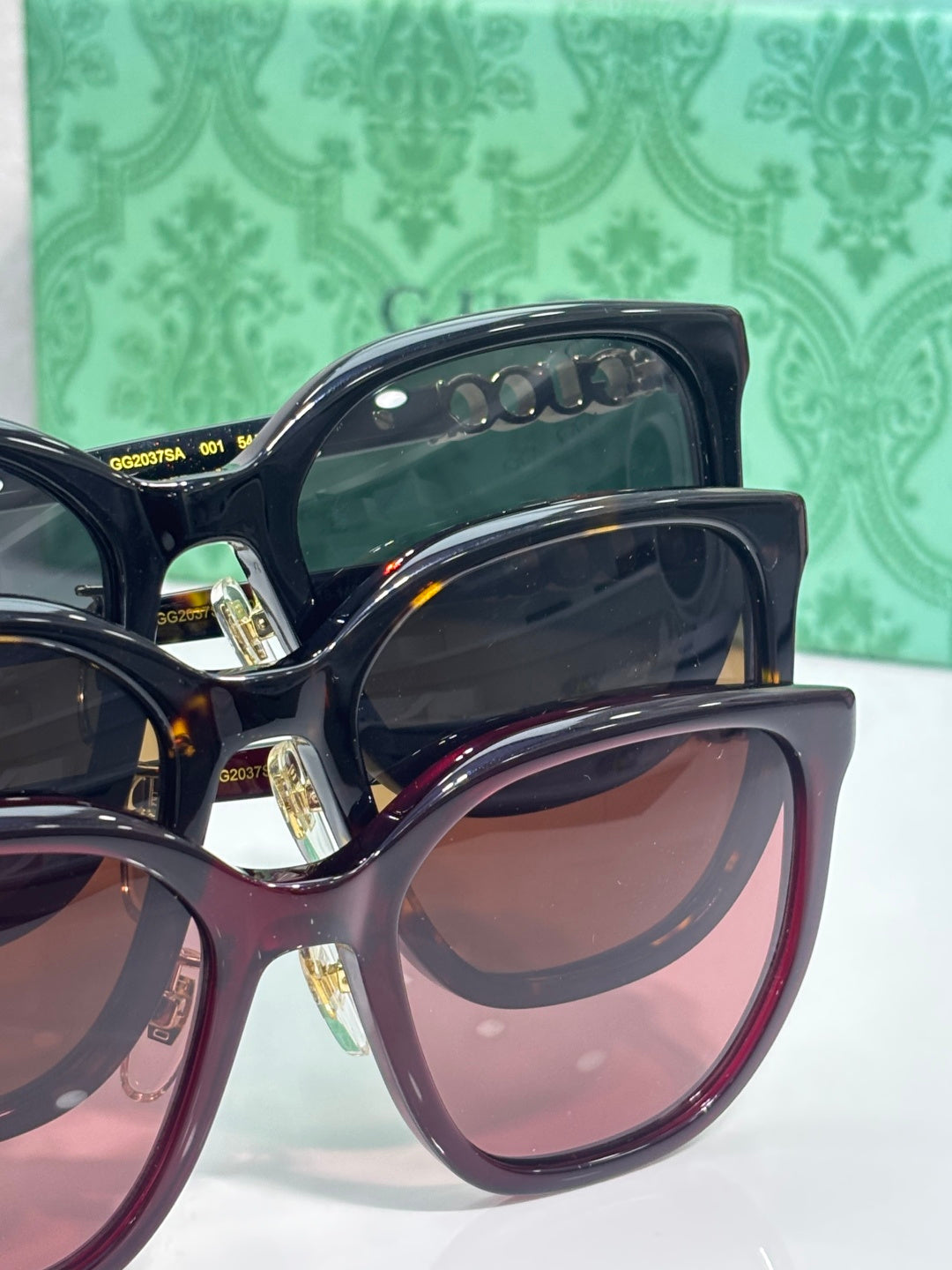 Dark navy square sunglasses with gold Gucci text on temple and tinted lenses