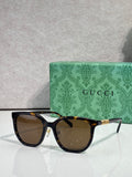 Black square sunglasses with brown lenses and gold Gucci logo on temples