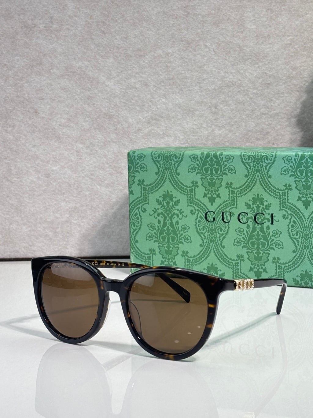 Gucci sunglasses with black frames and brown lenses, gold temple accents