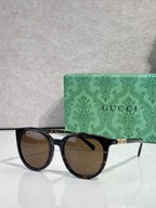 Gucci sunglasses with black frames and brown lenses, gold temple accents