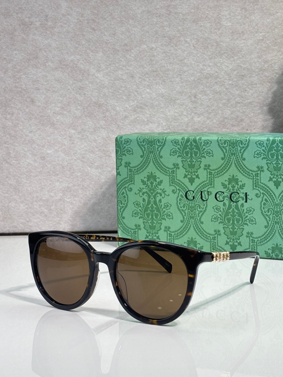 Gucci sunglasses with black frames and brown lenses, gold temple accents