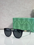 Gucci sunglasses with black frames and dark lenses, gold detail on temples