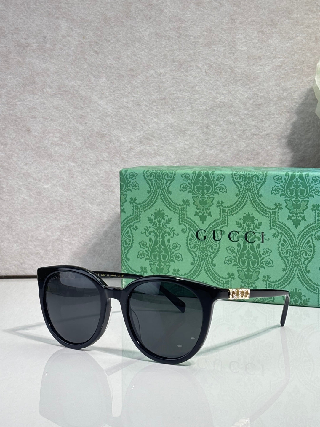 Gucci sunglasses with black frames and dark lenses, gold detail on temples