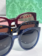 Layered view of Gucci sunglasses: maroon and dark blue frames with tinted lenses