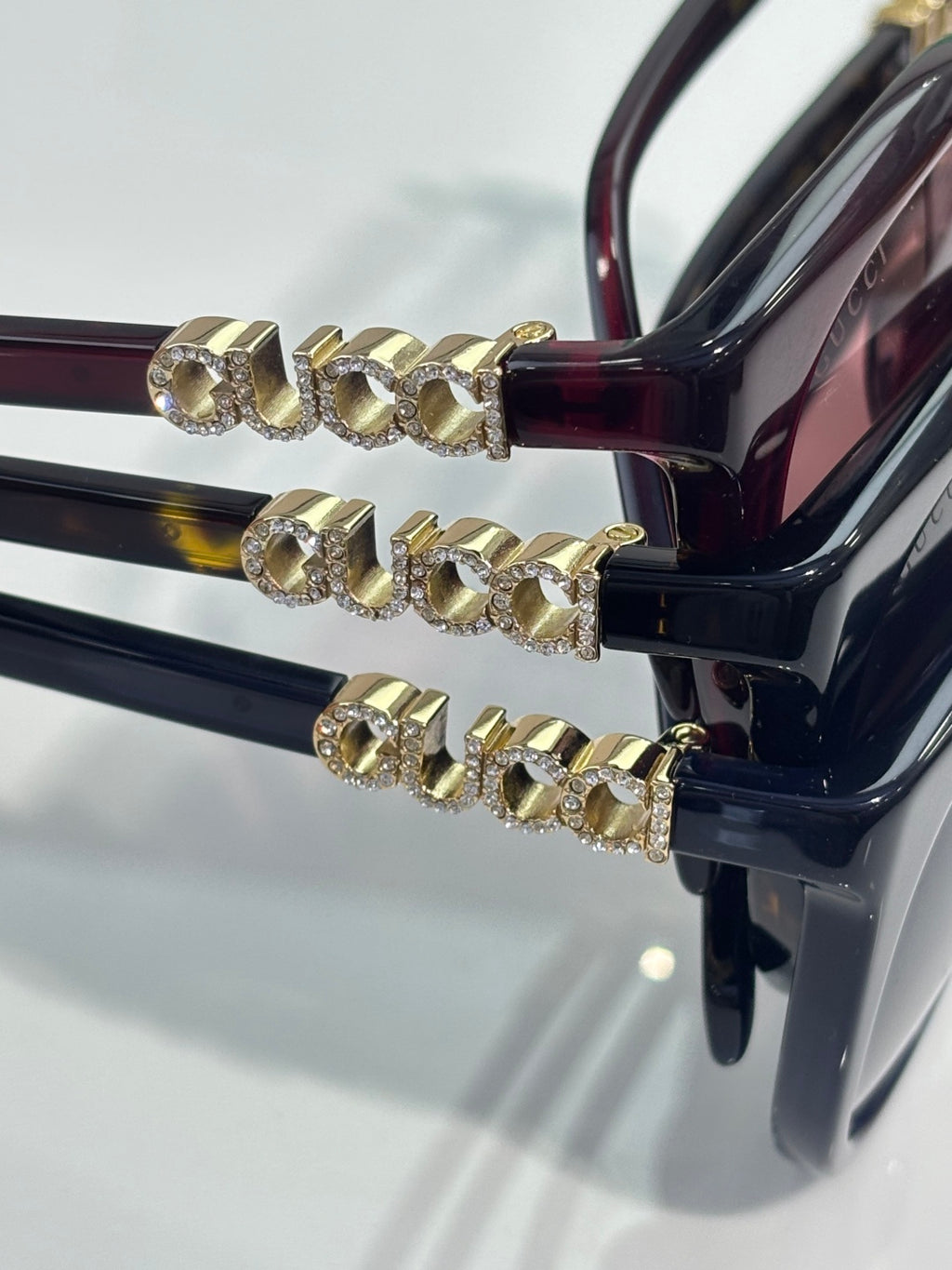 Gucci sunglasses temple close-up with gold logo links on dark frames