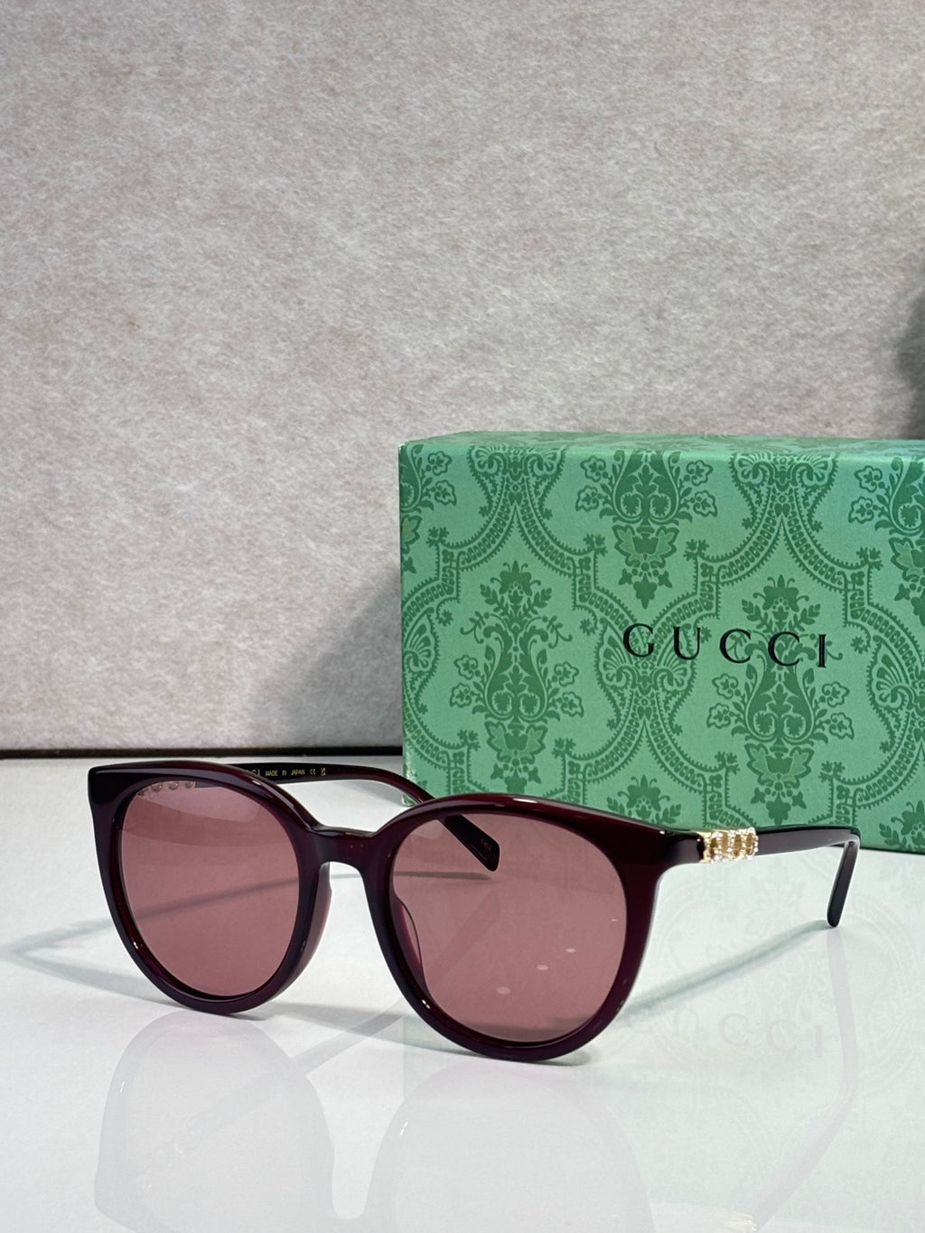 Gucci sunglasses with maroon frames and rose lenses, gold temple detailing